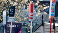 Estate agents' For Sale and To Let signs stand on display outside residential properties in London.